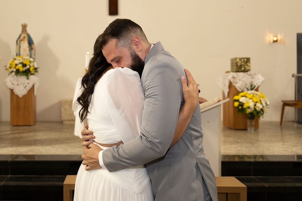 Diante do altar, os noivos se abraçam de olhos fechados.