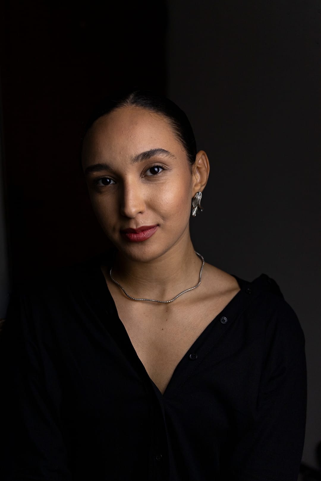 A Marcela na meia-luz, em preto e branco, olhando direto para a câmera.