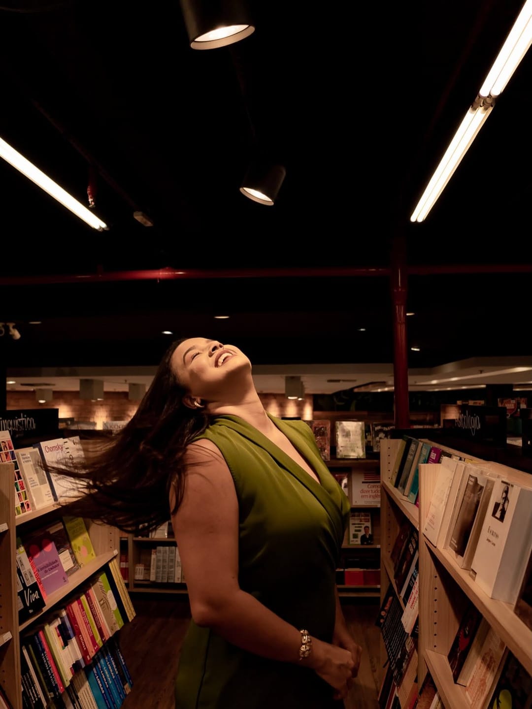 Uma mulher joga o cabelo entre as estantes de uma livraria.